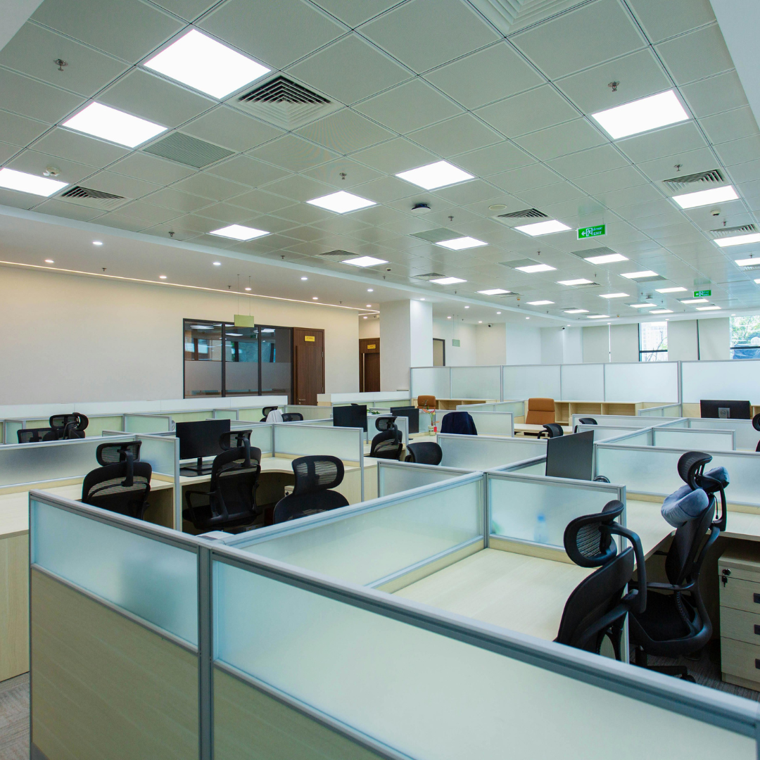 Open-plan office with workstations beneath grid ceiling lighting