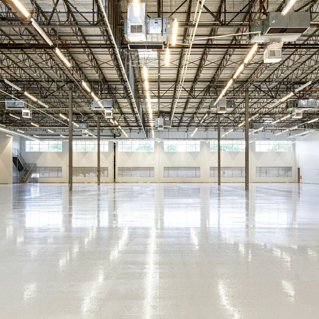 Large open warehouse floor beneath steel roof trusses